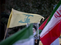 Iranian protesters wave a Lebanon's Hezbollah flag and an Iranian flag next to a portrait of Hezbollah Secretary General, Hassan Nasrallah,...