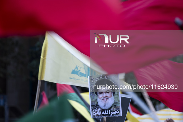 Iranian protesters wave a Lebanon's Hezbollah flag next to a portrait of Hezbollah Secretary General, Hassan Nasrallah, during a protest gat...