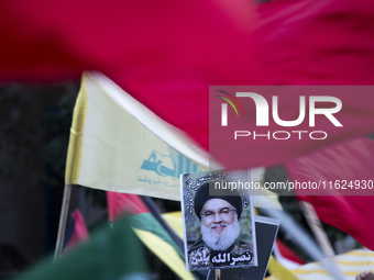 Iranian protesters wave a Lebanon's Hezbollah flag next to a portrait of Hezbollah Secretary General, Hassan Nasrallah, during a protest gat...