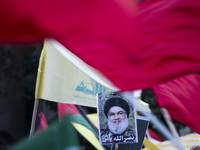 Iranian protesters wave a Lebanon's Hezbollah flag next to a portrait of Hezbollah Secretary General, Hassan Nasrallah, during a protest gat...