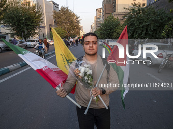 An Iranian protester carries an Iranian flag, a Palestinian flag, a flag of Lebanon's Hezbollah, and flowers while taking part in a protest...