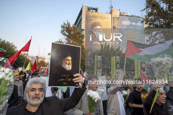 An Iranian protester carries a portrait of Lebanon's Hezbollah Secretary General, Hassan Nasrallah, during a protest gathering to condemn an...