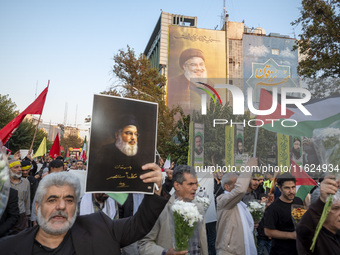 An Iranian protester carries a portrait of Lebanon's Hezbollah Secretary General, Hassan Nasrallah, during a protest gathering to condemn an...