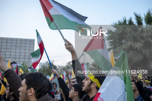 Iranian protesters wave Palestinian and Iranian flags while taking part in a protest gathering to condemn the Israeli air strike against Hez...