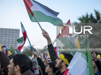 Iranian protesters wave Palestinian and Iranian flags while taking part in a protest gathering to condemn the Israeli air strike against Hez...