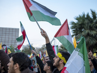 Iranian protesters wave Palestinian and Iranian flags while taking part in a protest gathering to condemn the Israeli air strike against Hez...