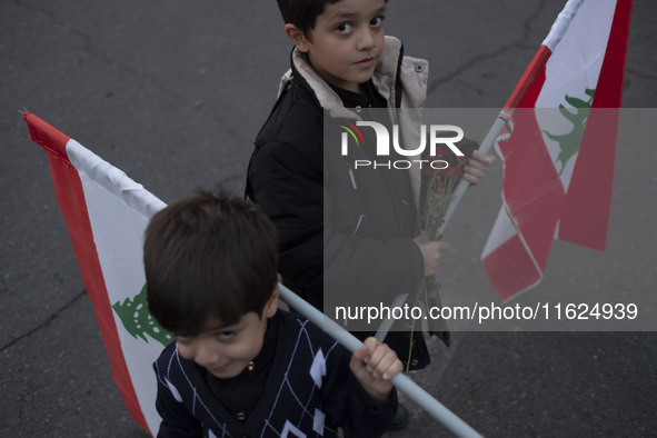 Two Iranian schoolboys hold Lebanese flags while taking part in a protest gathering with their parents (not pictured) to condemn an Israeli...