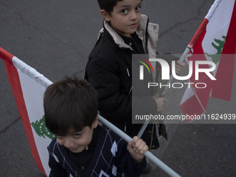 Two Iranian schoolboys hold Lebanese flags while taking part in a protest gathering with their parents (not pictured) to condemn an Israeli...