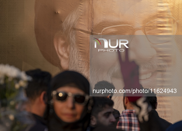 A veiled Iranian protester flashes a victory sign while standing in front of a giant banner depicting a portrait of Lebanon's Hezbollah Secr...