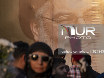 A veiled Iranian protester flashes a victory sign while standing in front of a giant banner depicting a portrait of Lebanon's Hezbollah Secr...