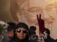 A veiled Iranian protester flashes a victory sign while standing in front of a giant banner depicting a portrait of Lebanon's Hezbollah Secr...