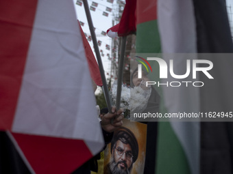 A veiled Iranian protester holds flowers and a portrait of Lebanon's Hezbollah Secretary General, Hassan Nasrallah, while standing behind a...