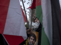 A veiled Iranian protester holds flowers and a portrait of Lebanon's Hezbollah Secretary General, Hassan Nasrallah, while standing behind a...