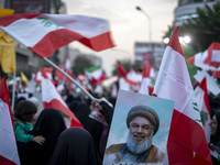 A veiled Iranian protester waves a Lebanese flag while standing behind a portrait of Lebanon's Hezbollah Secretary General, Hassan Nasrallah...