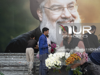 An Iranian protester holds flowers while standing in front of a giant banner depicting a portrait of Lebanon's Hezbollah Secretary General,...