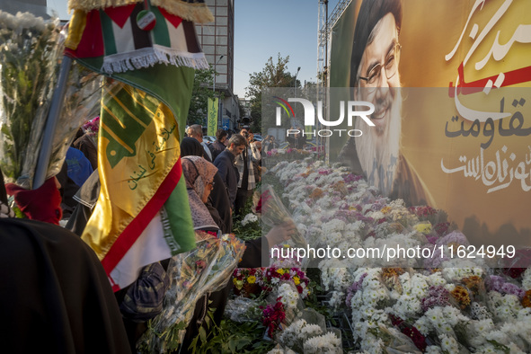 Iranian protesters place flowers under a giant banner featuring a portrait of Lebanon's Hezbollah Secretary General, Hassan Nasrallah, while...