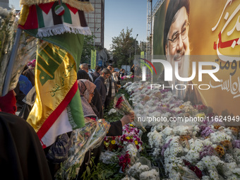 Iranian protesters place flowers under a giant banner featuring a portrait of Lebanon's Hezbollah Secretary General, Hassan Nasrallah, while...