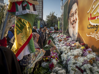 Iranian protesters place flowers under a giant banner featuring a portrait of Lebanon's Hezbollah Secretary General, Hassan Nasrallah, while...