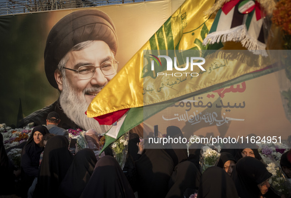 Iranian protesters carry flowers while standing in front of a giant banner depicting a portrait of Lebanon's Hezbollah Secretary General, Ha...