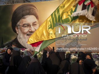 Iranian protesters carry flowers while standing in front of a giant banner depicting a portrait of Lebanon's Hezbollah Secretary General, Ha...