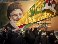 Iranian protesters carry flowers while standing in front of a giant banner depicting a portrait of Lebanon's Hezbollah Secretary General, Ha...