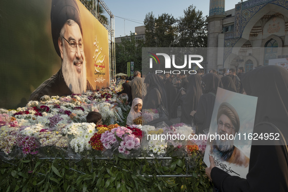 Iranian protesters place flowers under a giant banner featuring a portrait of Lebanon's Hezbollah Secretary General, Hassan Nasrallah, while...