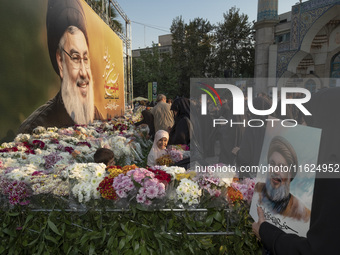 Iranian protesters place flowers under a giant banner featuring a portrait of Lebanon's Hezbollah Secretary General, Hassan Nasrallah, while...