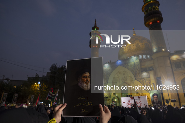 A veiled Iranian protester holds up a portrait of Lebanon's Hezbollah Secretary General, Hassan Nasrallah, while taking part in a protest ga...