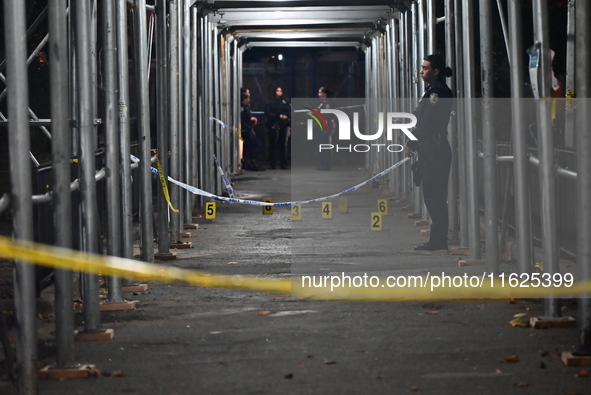 Crime scene investigators mark evidence at the scene where one man is killed and two other men are injured following a shooting in Bedford-S...