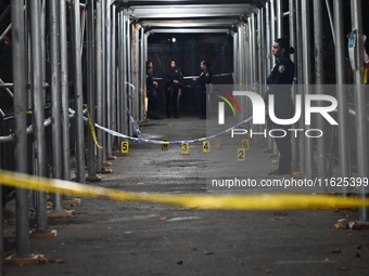 Crime scene investigators mark evidence at the scene where one man is killed and two other men are injured following a shooting in Bedford-S...