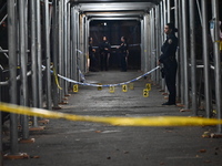 Crime scene investigators mark evidence at the scene where one man is killed and two other men are injured following a shooting in Bedford-S...