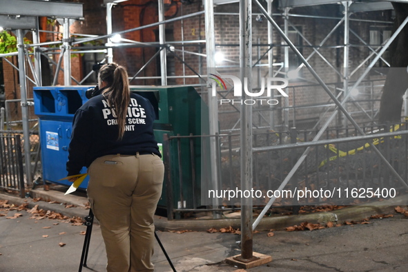 Crime scene investigators mark evidence at the scene where one man is killed and two other men are injured following a shooting in Bedford-S...