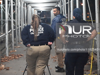 Crime scene investigators mark evidence at the scene where one man is killed and two other men are injured following a shooting in Bedford-S...