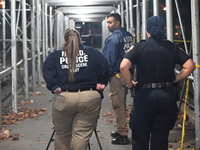 Crime scene investigators mark evidence at the scene where one man is killed and two other men are injured following a shooting in Bedford-S...