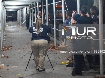 Crime scene investigators mark evidence at the scene where one man is killed and two other men are injured following a shooting in Bedford-S...