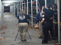 Crime scene investigators mark evidence at the scene where one man is killed and two other men are injured following a shooting in Bedford-S...