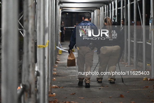 Crime scene investigators mark evidence at the scene where one man is killed and two other men are injured following a shooting in Bedford-S...