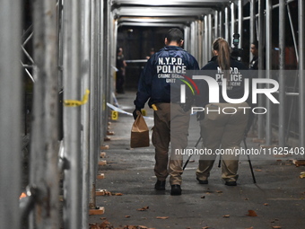 Crime scene investigators mark evidence at the scene where one man is killed and two other men are injured following a shooting in Bedford-S...