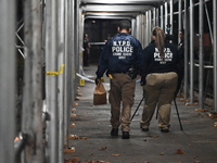 Crime scene investigators mark evidence at the scene where one man is killed and two other men are injured following a shooting in Bedford-S...