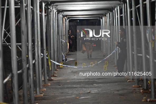 Crime scene investigators mark evidence at the scene where one man is killed and two other men are injured following a shooting in Bedford-S...