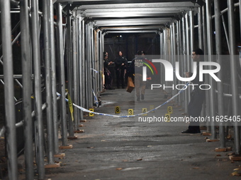 Crime scene investigators mark evidence at the scene where one man is killed and two other men are injured following a shooting in Bedford-S...