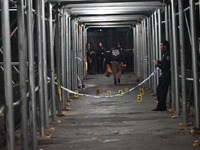 Crime scene investigators mark evidence at the scene where one man is killed and two other men are injured following a shooting in Bedford-S...