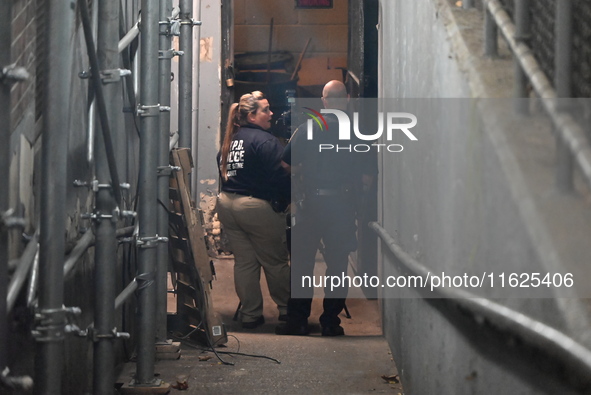 Crime scene investigators mark evidence at the scene where one man is killed and two other men are injured following a shooting in Bedford-S...