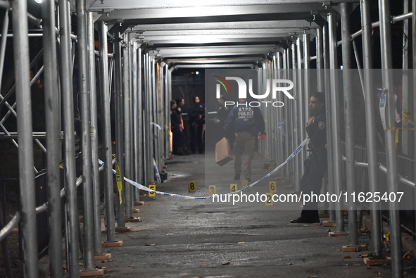 Crime scene investigators mark evidence at the scene where one man is killed and two other men are injured following a shooting in Bedford-S...