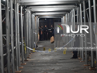 Crime scene investigators mark evidence at the scene where one man is killed and two other men are injured following a shooting in Bedford-S...