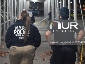 Crime scene investigators mark evidence at the scene where one man is killed and two other men are injured following a shooting in Bedford-S...