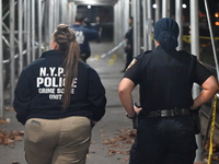 Crime scene investigators mark evidence at the scene where one man is killed and two other men are injured following a shooting in Bedford-S...