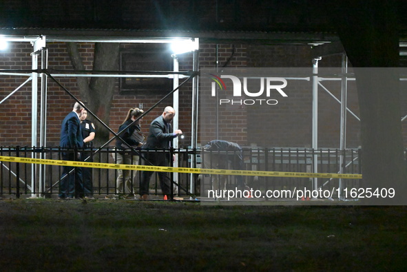 Crime scene investigators mark evidence at the scene where one man is killed and two other men are injured following a shooting in Bedford-S...