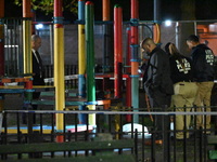 Crime scene investigators mark evidence at the scene where one man is killed and two other men are injured following a shooting in Bedford-S...