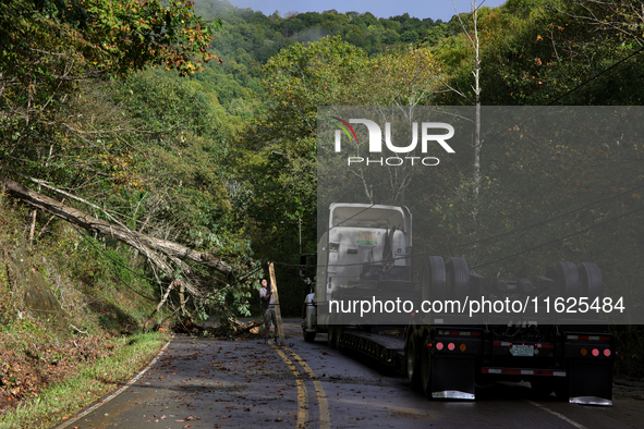 A truck driver works to remove entangled wires after passing through a damaged roadway in Whitetop, Virginia on September 30, 2024 after Hur...